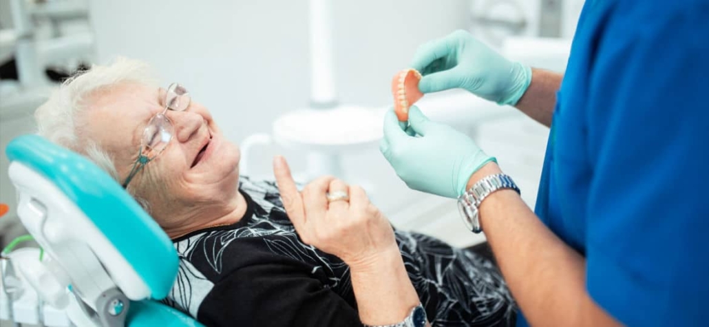 Elderly woman in a dental chair being given her new denture by the denturist for insertion