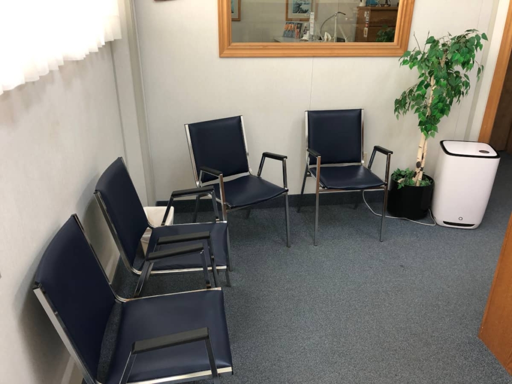 Waiting room of Tim Schankula's Grantham Denture Clinic, showing 4 chairs, a large plant and an large air purifier on the floor