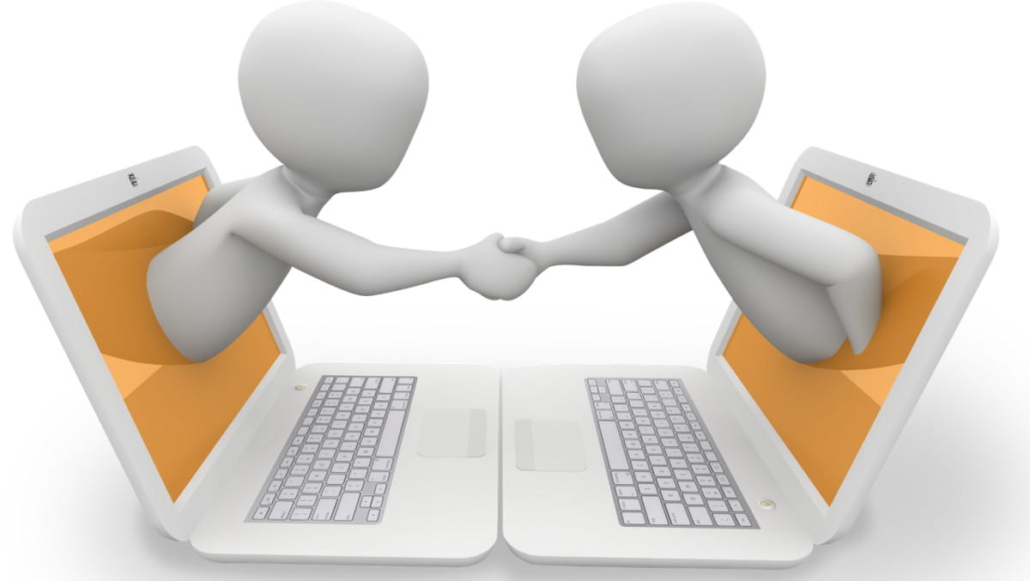 Diagram of two laptops with two graphic people coming out of the screens shaking hands